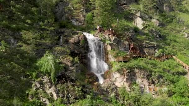 Drone plující přes zelený les s vodopádem v pohoří Altai. — Stock video