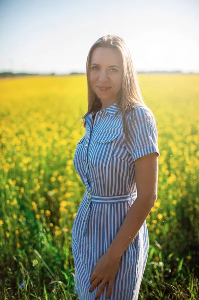 Vacker kvinna i fält med gula blommor — Stockfoto
