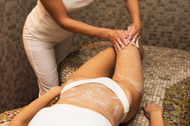 Woman having massage with cream at spa clipart