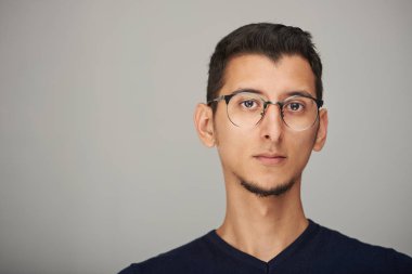 Gri arka plan üzerinde izole ciddi genç İspanyol adam portresi