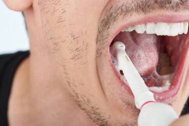 Adam dişlerini fırçalıyor.