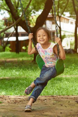 Bir parkta oynarken bir salıncak üzerinde Asyalı kız