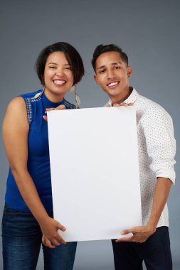 Gülümseyen iki izole studio arka plan üzerinde beyaz afiş tutun
