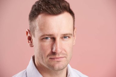 Beyaz seriuos genç adam, pembe arka plan izole headshot