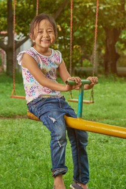 Asyalı kız teetertotter bir parkta oynamaya. Filipina çocuk.