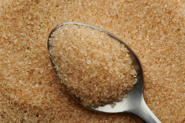 Brown sugar crystals in metal spoon — Stock Photo, Image