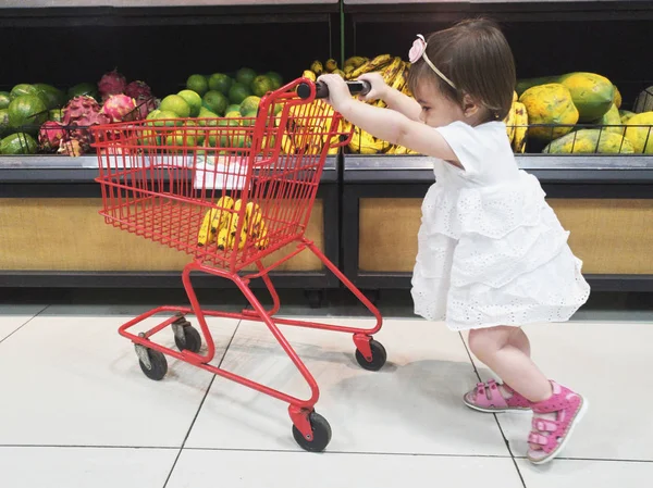 Bebek kız alışveriş sepeti iterek — Stok fotoğraf