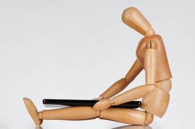 Tahta oyuncak beyaz arka planda izole akıllı telefona bak