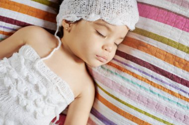 Renkli yatakta uyuyan güzel bir kız bebek. Yakın plan.