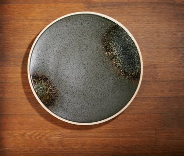 Kahverengi ahşap masanın üstünde, gri, pis bir tabak.