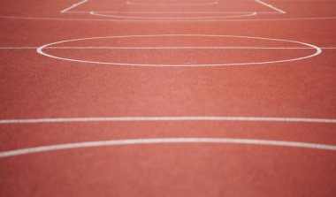 Güneşli bir günde kırmızı boş basketbol sahasında beyaz çizgiler