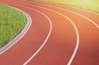 Parlak güneşli ışıkta kırmızı şeritlerde koşan sporcu