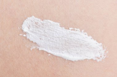 Bej rengi deri dokusu üzerinde nemlendirici beyaz krem vuruşu