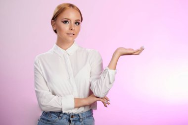 Avuç içi boş genç bir kadın pembe arka planda izole edilmiş.