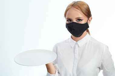 Beyaz stüdyo arka planında boş tabağı olan genç bir kadın.
