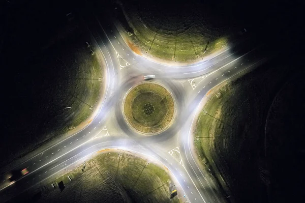 Streets with roundabout at night time light above drone view