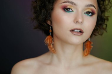 Çıplak omuzlu ve kıvırcık saçlı bir kadının portresi.