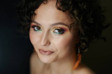 Siyah arka planda makyajlı genç bir kadın.