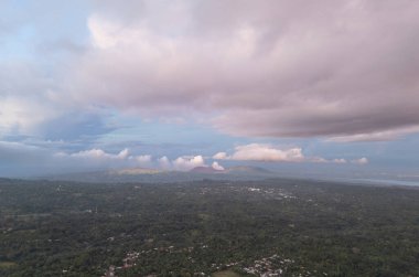 Renkli gökyüzü altında yuvarlanan tepeler ve kabarık bulutlar kırsal alanda günbatımında çekilen güzel manzara gösterileri..