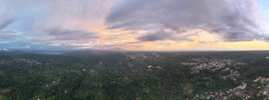 Parlak günbatımı, zengin yeşil ormanlar ve aşağıdaki huzurlu kasabanın yakınlarındaki uzak dağların üzerine renkli bir ışık saçar..