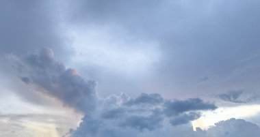 Dark gray and white clouds fill the sky as the sun sets, creating a peaceful yet dramatic atmosphere at dusk.