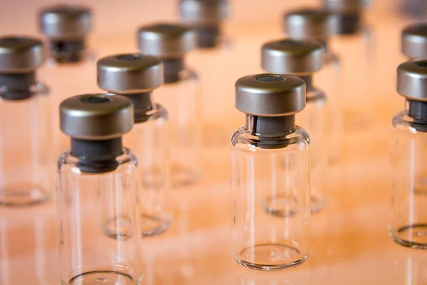 Butelki szklane szczepionki na pomarańczowym tle — Zdjęcie stockowe