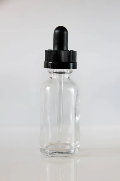 Bottiglia contagocce di vetro su sfondo grigio — Foto Stock