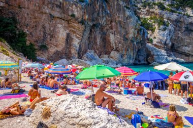 Sardinya / İtalya - 26 Ağustos 2019 - Orosei Golfü 'ndeki Cala Mariolu plajında bir grup turist
