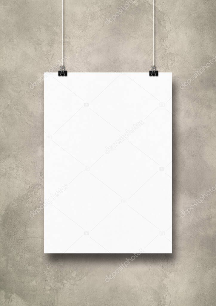 White poster hanging on a light concrete wall with clips. Blank mockup template