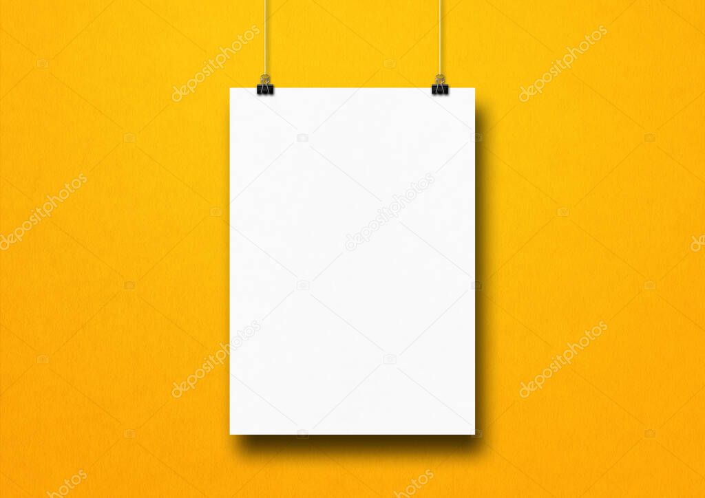 White poster hanging on a yellow wall with clips. Blank mockup template