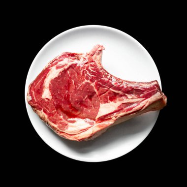 Siyah arka planda izole edilmiş bir tabakta çiğ dana pirzolası. Üst görünüm