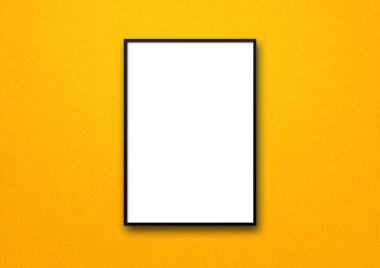 Sarı bir duvarda asılı siyah resim çerçevesi. Boş model şablonu