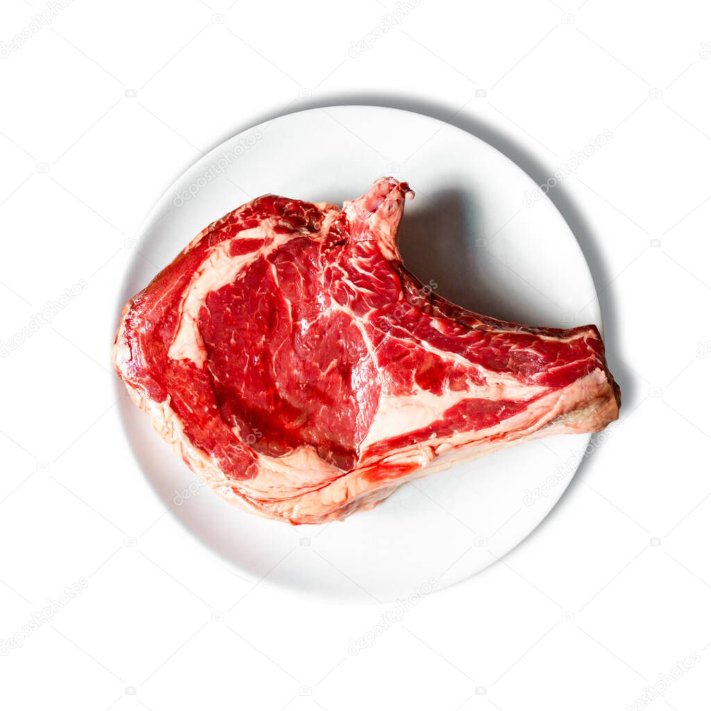 Raw beef prime rib on a plate isolated on white background. Top view