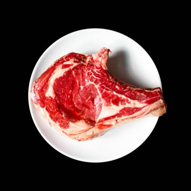 Siyah arka planda izole edilmiş bir tabakta çiğ dana pirzolası. Üst görünüm