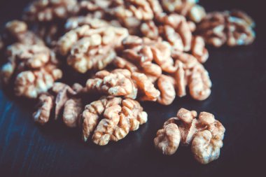 Siyah ahşap bir masada ceviz çekirdekleri. Yakın görünüm