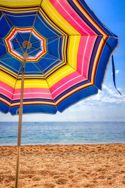 Tropikal bir sahilde renkli bir şemsiye.