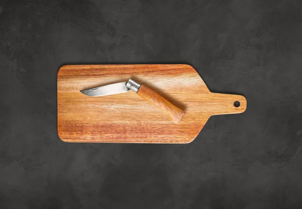 コンクリートテーブルの背景に木製のまな板とポケットナイフ — ストック写真