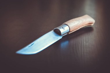 Eski ahşap çakı, siyah ahşap masa arkasında.