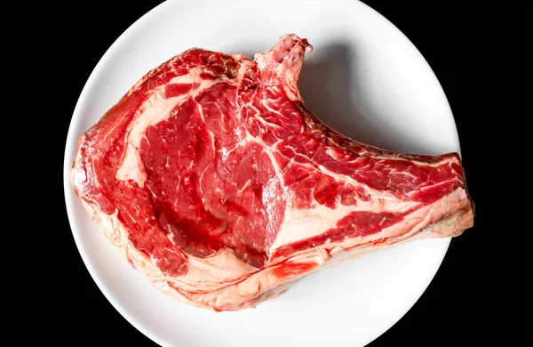 Siyah arka planda izole edilmiş bir tabakta çiğ dana pirzolası. Üst görünüm