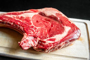 Siyah arka planda izole edilmiş bir kesme tahtasındaki çiğ sığır pirzolası.