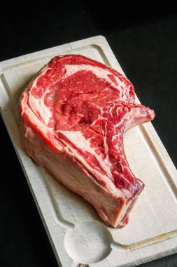 Siyah arka planda izole edilmiş bir kesme tahtasındaki çiğ sığır pirzolası.