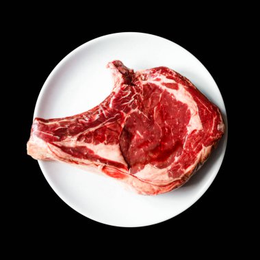 Siyah arka planda izole edilmiş bir tabakta çiğ dana pirzolası. Üst görünüm