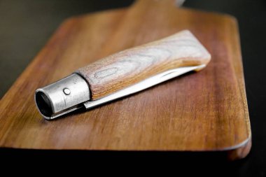 Siyah mutfak masasında tahta kesme tahtası ve çakı.