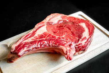 Siyah arka planda izole edilmiş bir kesme tahtasındaki çiğ sığır pirzolası.