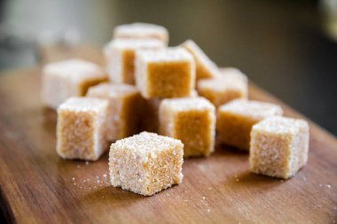 Tahta kesme tahtasının üzerinde kahverengi kamış şeker küpleri