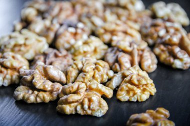 Siyah ahşap bir masada ceviz çekirdekleri. Yakın görünüm