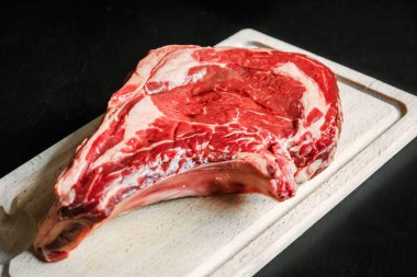 Siyah arka planda izole edilmiş bir kesme tahtasındaki çiğ sığır pirzolası.