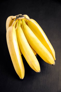 Siyah ahşap bir masada bir avuç organik muz.