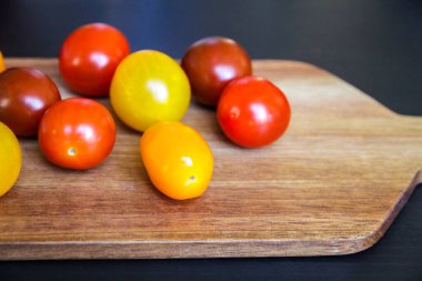 Ahşap kesme tahtasında renkli domatesler.