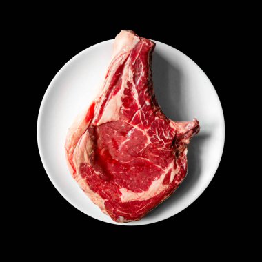 Siyah arka planda izole edilmiş bir tabakta çiğ dana pirzolası. Üst görünüm